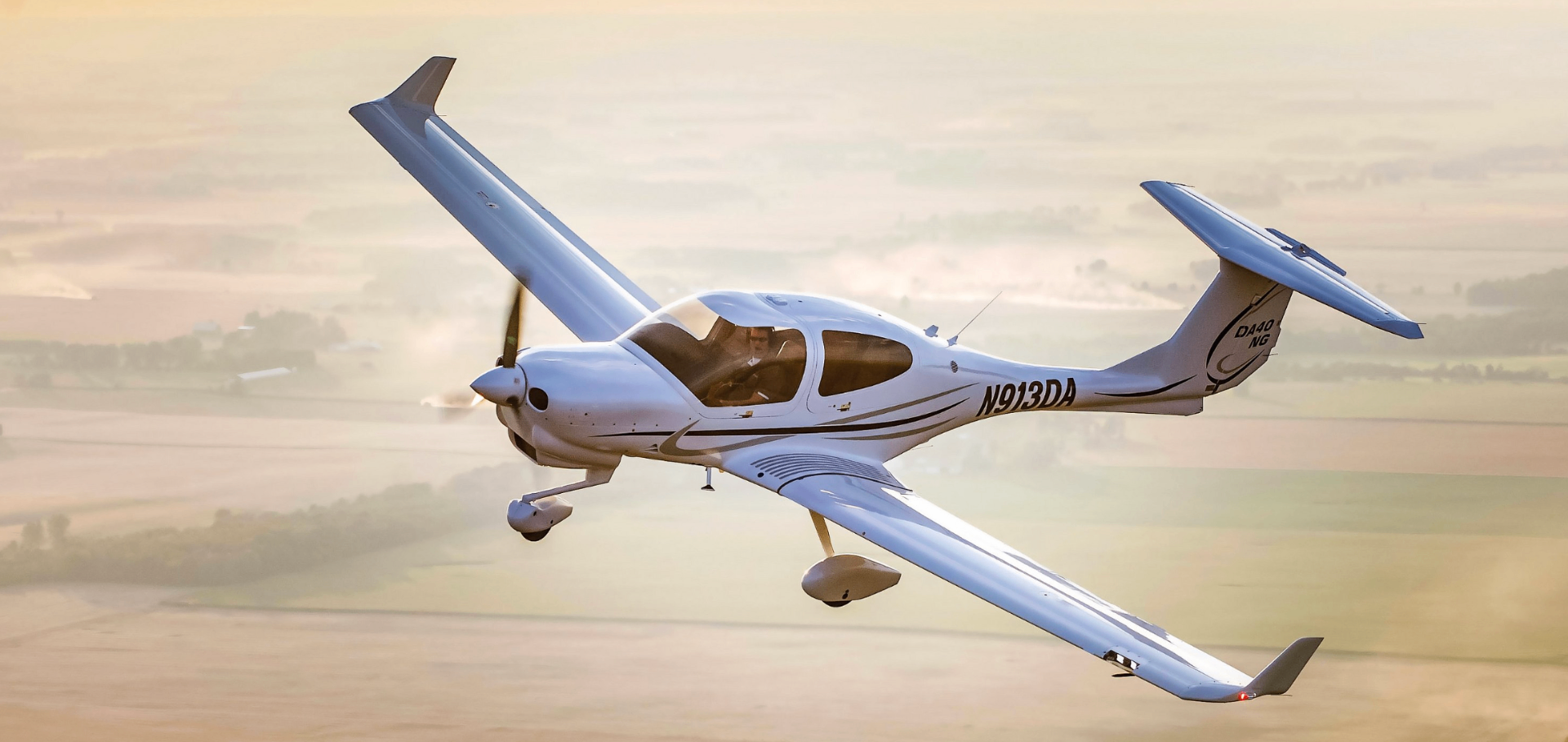 Diamond DA40 NG i luften över böljande landskap i gyllene ljus