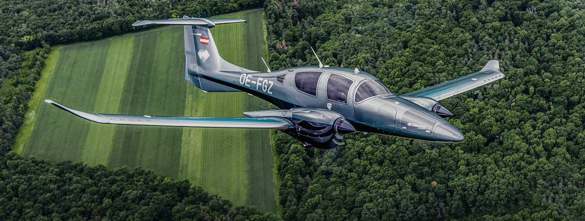 Diamond DA62 i metallic-grå lackering över skog och fält