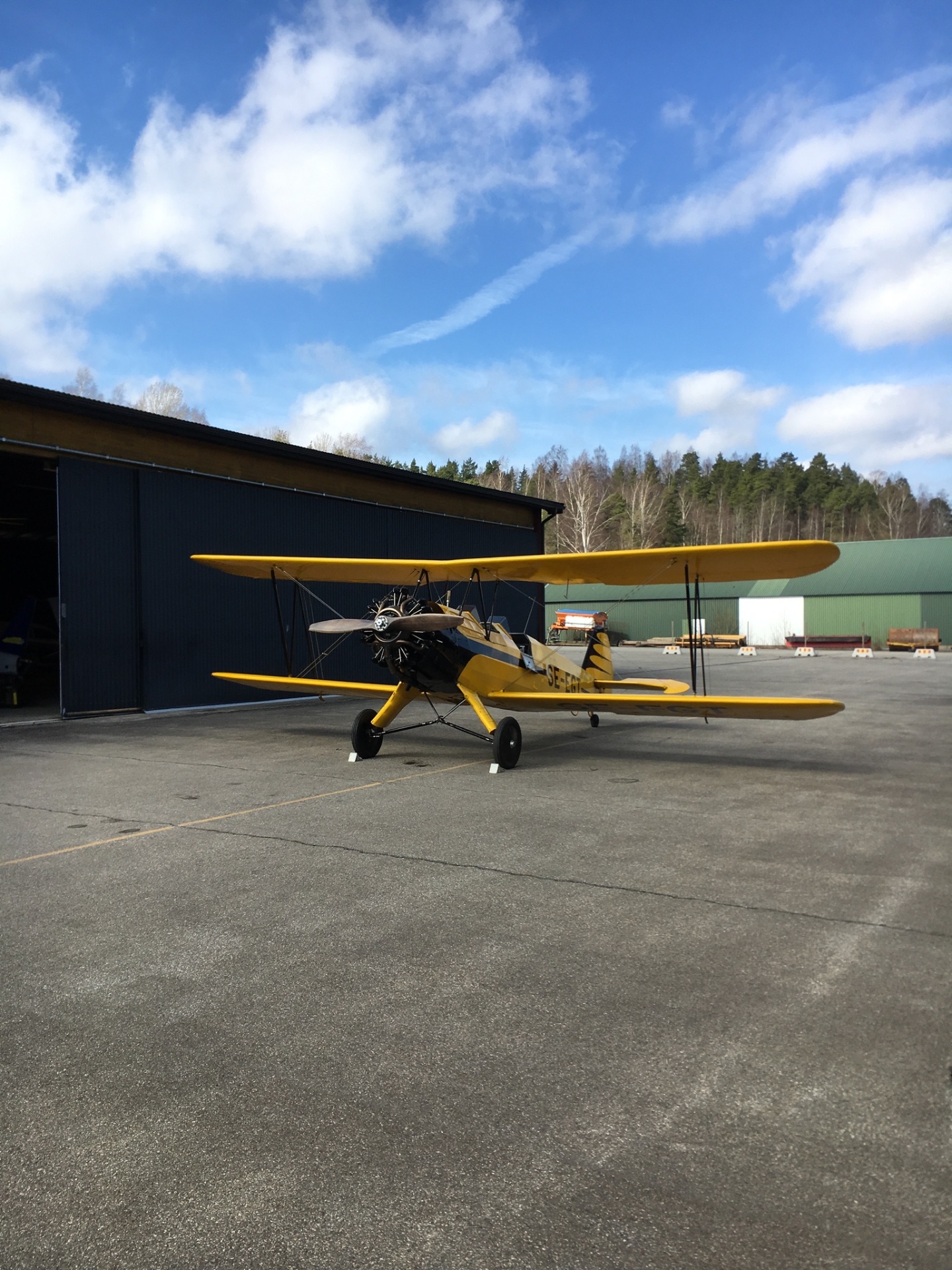 Gul Stearman biplan framför hangaren